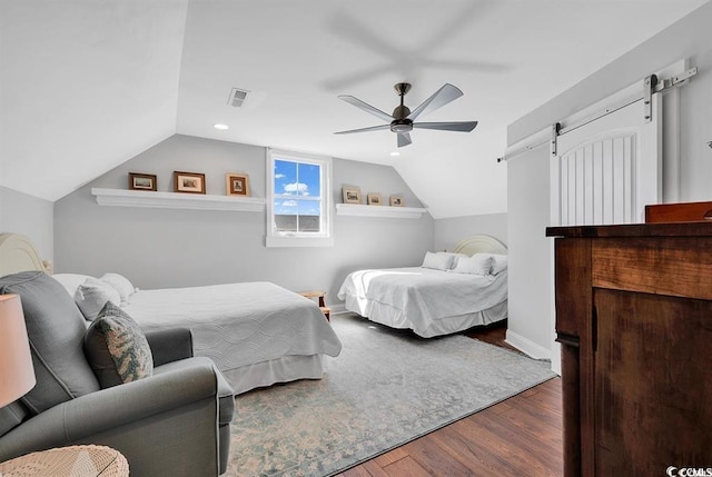 bedroom featuring ceiling fan, lofted ceiling, wood-type flooring, and a barn door