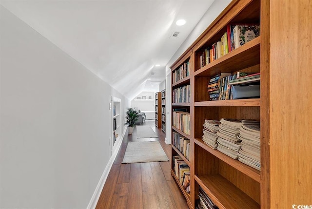 hallway featuring hardwood / wood-style flooring, vaulted ceiling, and built in features