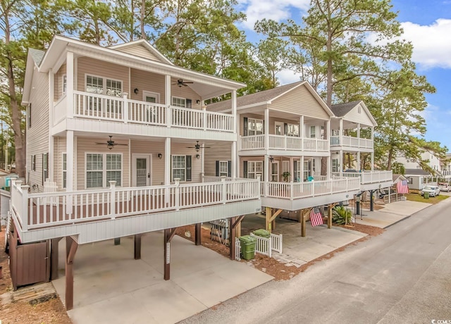 coastal inspired home with ceiling fan, driveway, central AC unit, and a balcony