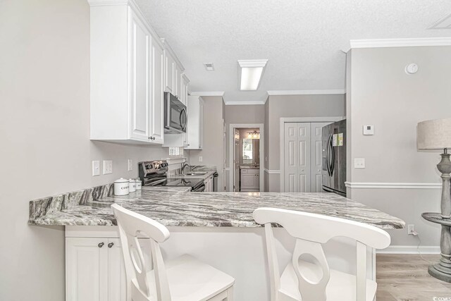 kitchen with a textured ceiling, stainless steel appliances, a peninsula, white cabinetry, and crown molding