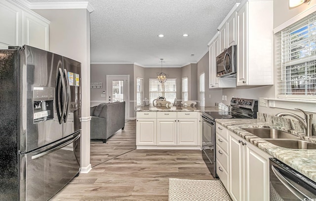 kitchen with crown molding, light wood-style flooring, appliances with stainless steel finishes, white cabinets, and a sink