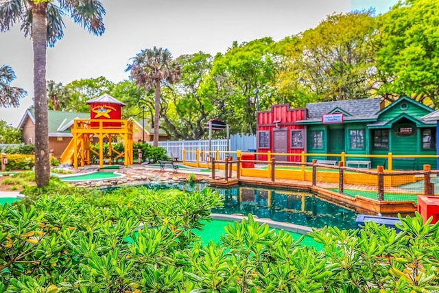 view of swimming pool featuring playground community and fence