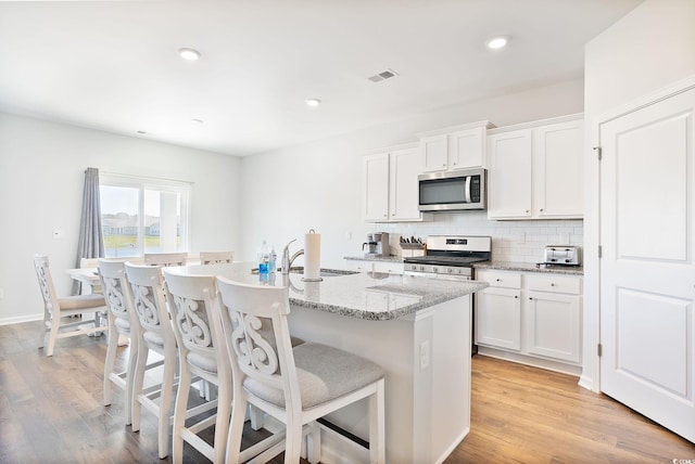 kitchen featuring a sink, stainless steel appliances, light wood-style floors, and decorative backsplash