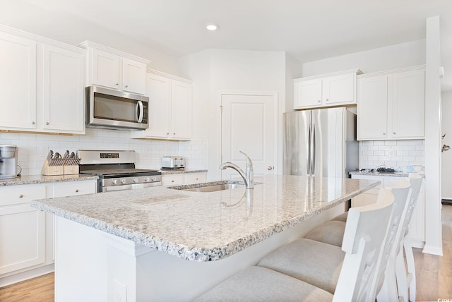 kitchen featuring white cabinets, appliances with stainless steel finishes, light wood-style floors, and a sink