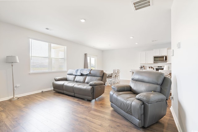 living room featuring visible vents, baseboards, and wood finished floors