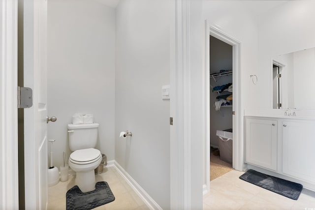 bathroom with vanity, baseboards, a spacious closet, tile patterned floors, and toilet