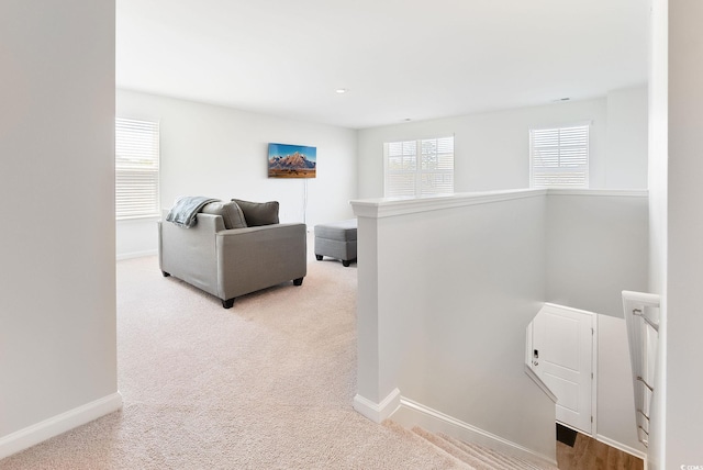 hallway featuring an upstairs landing, light colored carpet, and baseboards