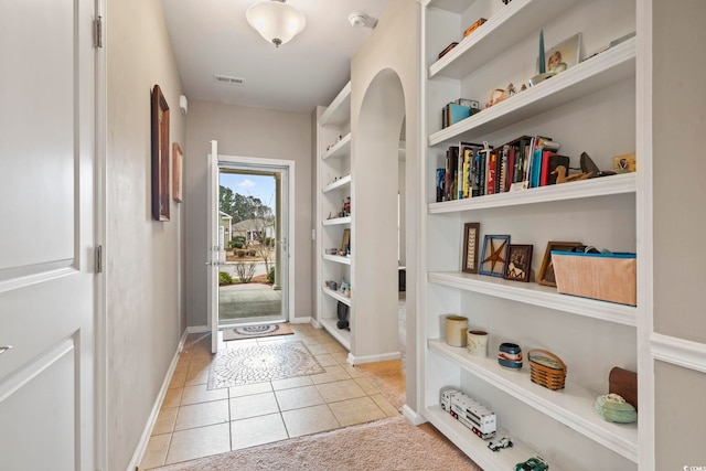 doorway to outside with light tile patterned flooring, visible vents, and baseboards