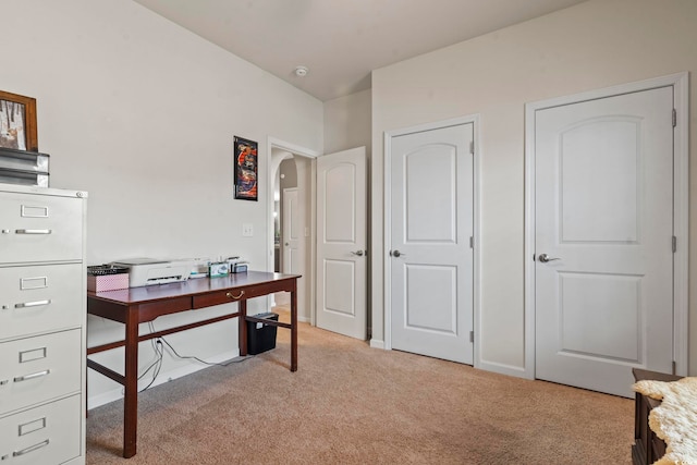 office with arched walkways, light colored carpet, and baseboards