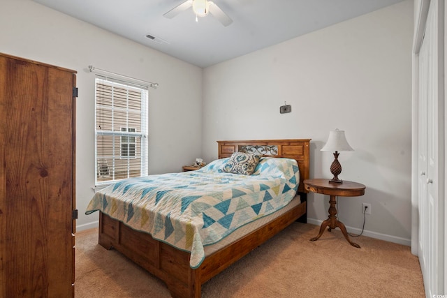 bedroom with visible vents, light colored carpet, baseboards, and ceiling fan