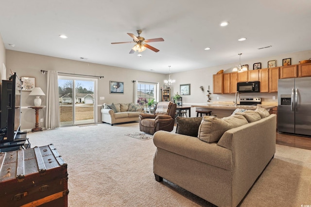 living room featuring visible vents, recessed lighting, ceiling fan with notable chandelier, and light colored carpet