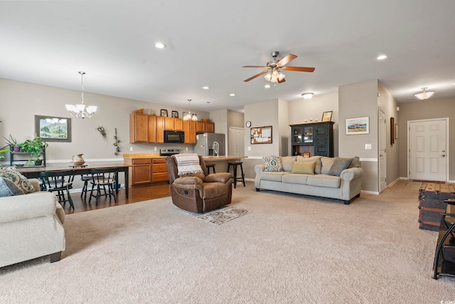 living area with recessed lighting, light colored carpet, ceiling fan with notable chandelier, and baseboards