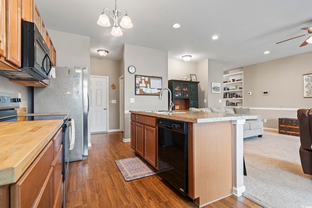 kitchen featuring black appliances, ceiling fan with notable chandelier, a sink, open floor plan, and dark wood finished floors