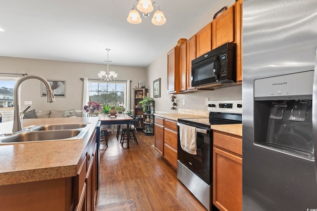 kitchen featuring brown cabinets, a sink, dark wood finished floors, appliances with stainless steel finishes, and a chandelier