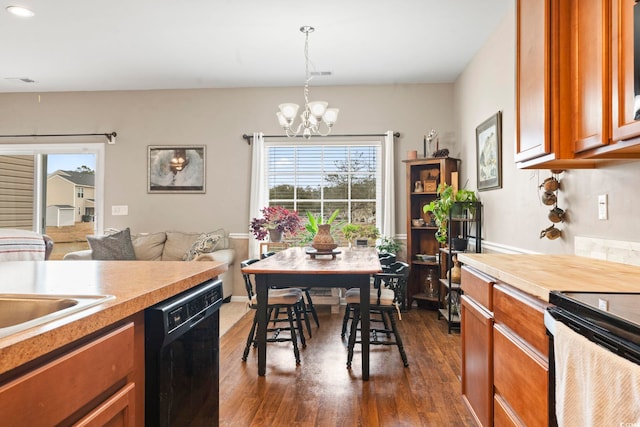 kitchen featuring dark wood-style floors, light countertops, black dishwasher, brown cabinets, and a chandelier