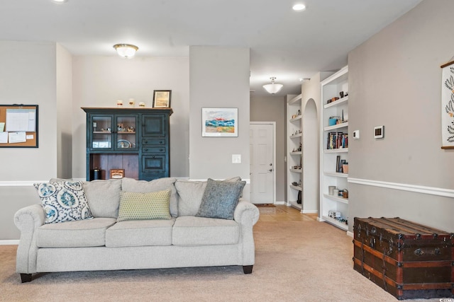 living room with built in features, baseboards, and light carpet