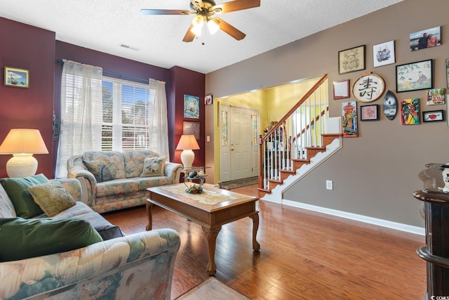 living room with hardwood / wood-style flooring, ceiling fan, and a textured ceiling