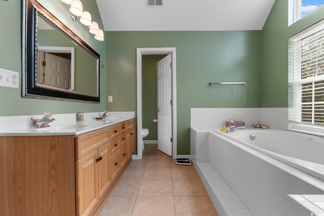 bathroom with tiled tub, vaulted ceiling, tile patterned floors, and toilet