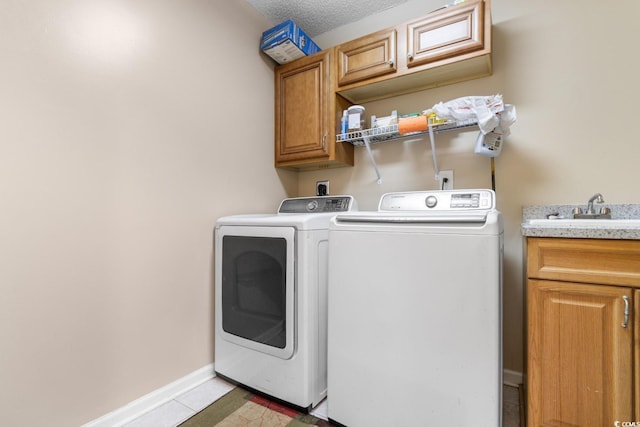 laundry room with sink, washer and clothes dryer, cabinets, a textured ceiling, and light tile patterned flooring