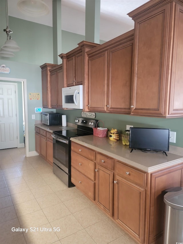 kitchen with electric stove, white microwave, light tile patterned floors, and light countertops