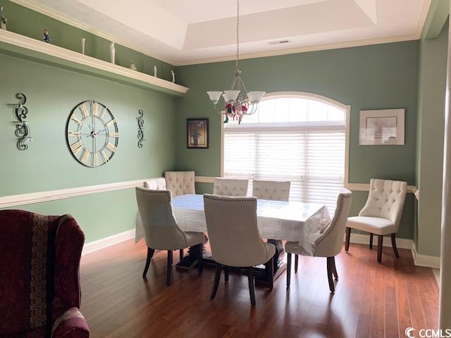 dining area featuring a raised ceiling, a chandelier, wood finished floors, and baseboards