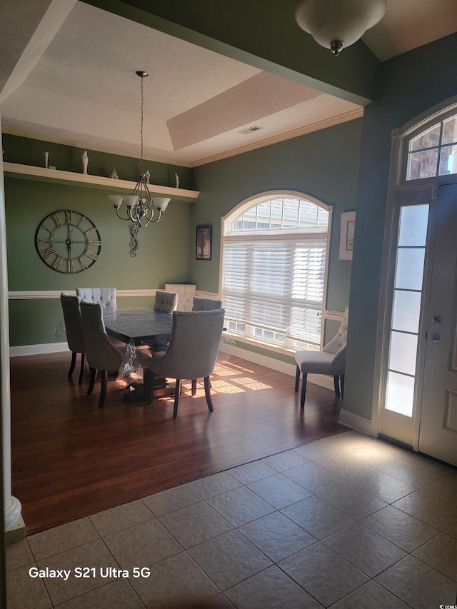 dining area with visible vents, a chandelier, a raised ceiling, and baseboards