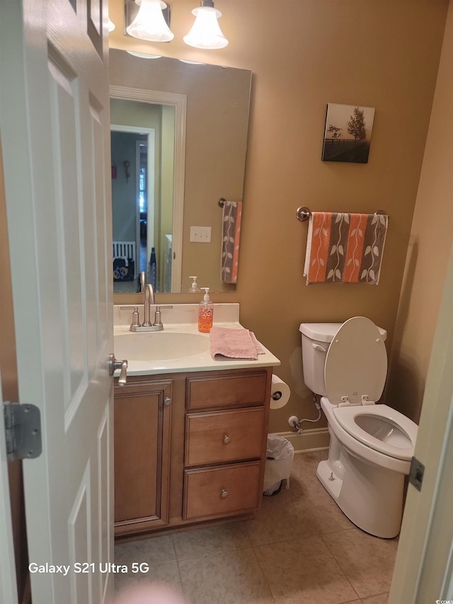 bathroom with tile patterned flooring, baseboards, vanity, and toilet