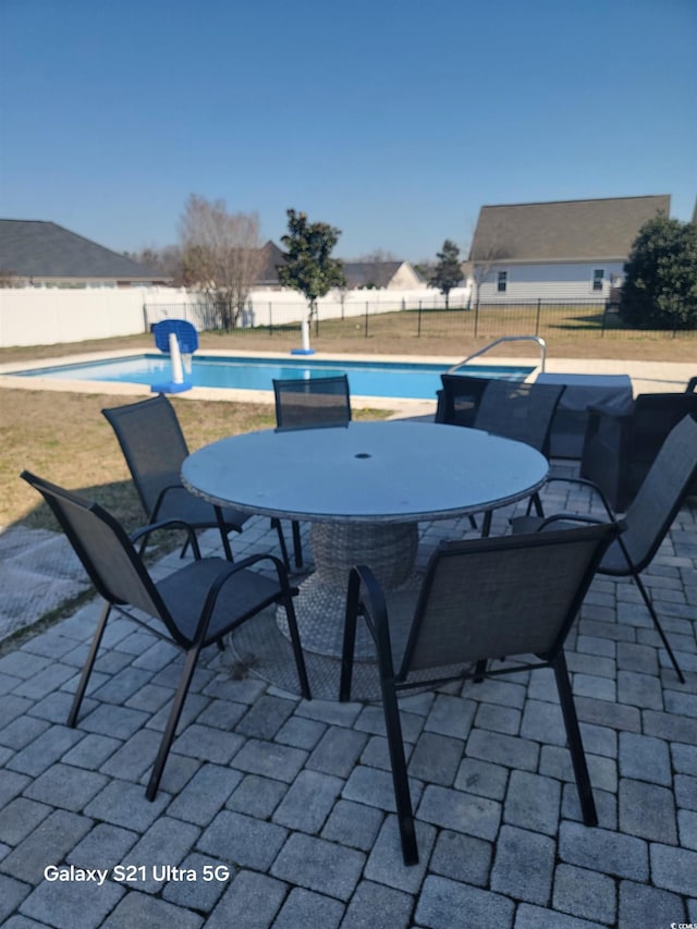 view of patio / terrace featuring fence, outdoor dining area, and a fenced in pool