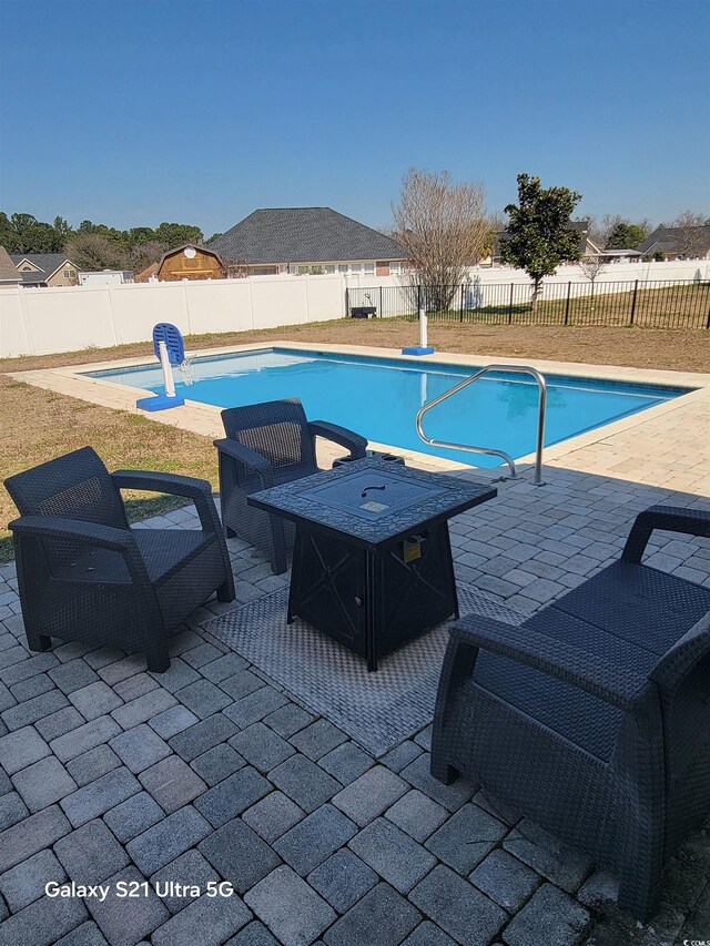 view of swimming pool with a fenced backyard, a patio, and an outdoor fire pit