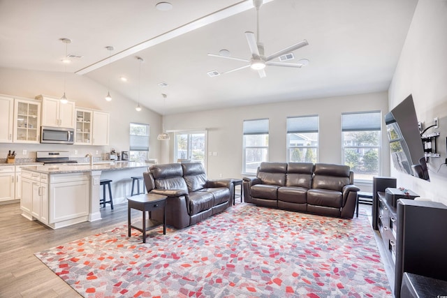 living room featuring vaulted ceiling with beams, ceiling fan, and light hardwood / wood-style flooring