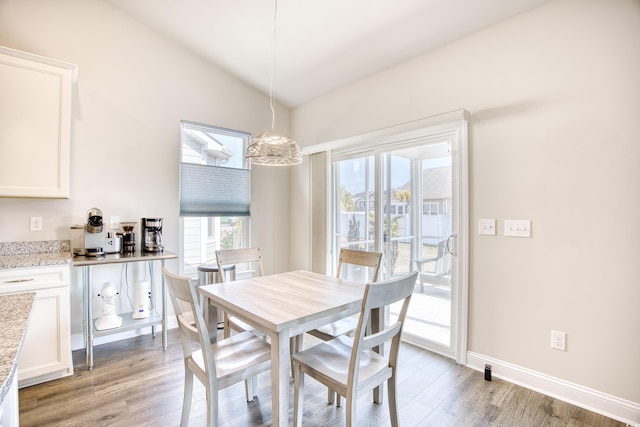 dining room featuring vaulted ceiling and light hardwood / wood-style flooring