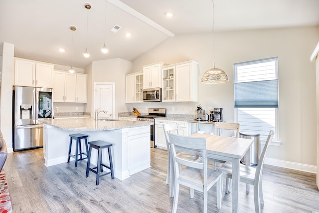 kitchen with pendant lighting, sink, an island with sink, and appliances with stainless steel finishes