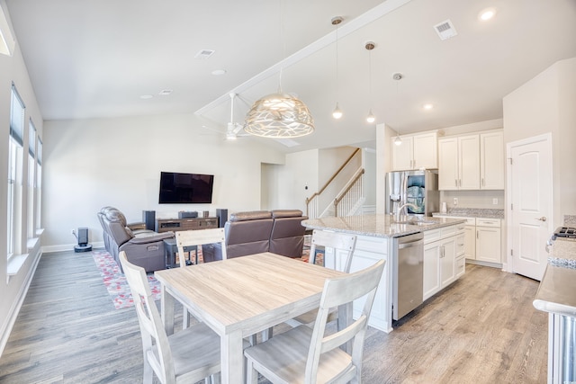 kitchen featuring white cabinetry, hanging light fixtures, light stone counters, and stainless steel appliances