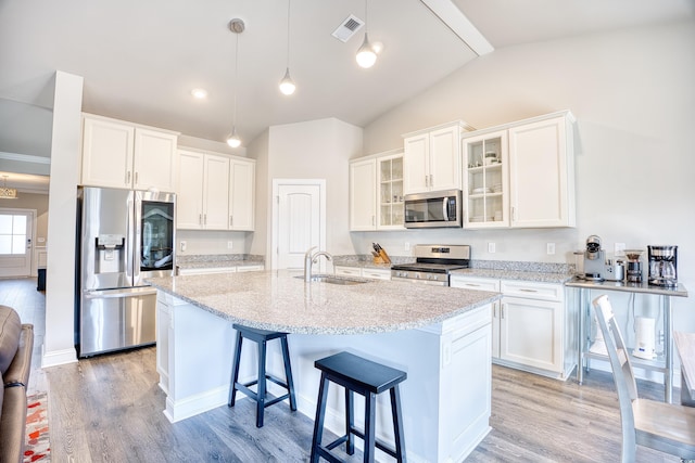 kitchen with appliances with stainless steel finishes, white cabinetry, a breakfast bar area, hanging light fixtures, and a kitchen island with sink