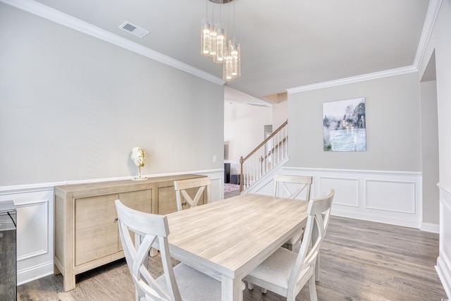 dining space with a notable chandelier, hardwood / wood-style flooring, and ornamental molding