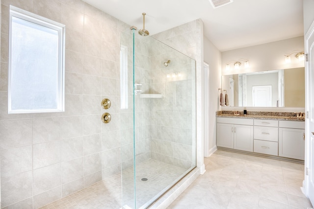 bathroom with vanity, tile patterned flooring, and a tile shower