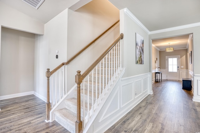 stairs with hardwood / wood-style flooring and ornamental molding