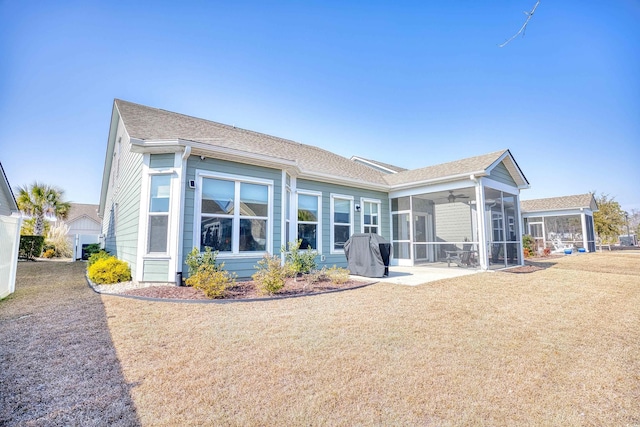 rear view of house with a sunroom, a lawn, and a patio area