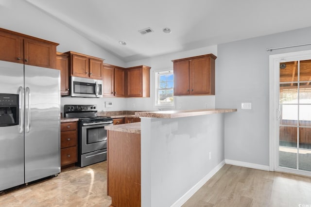 kitchen with stainless steel appliances, vaulted ceiling, light wood-type flooring, and kitchen peninsula