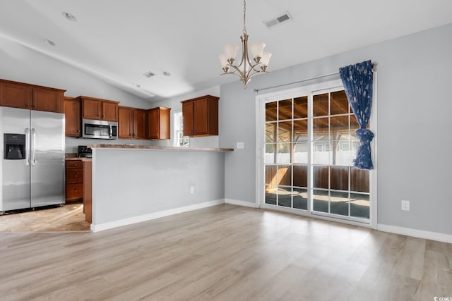 kitchen with vaulted ceiling, hanging light fixtures, light wood-type flooring, appliances with stainless steel finishes, and kitchen peninsula