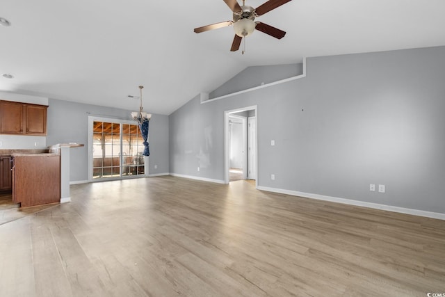 unfurnished living room with lofted ceiling, ceiling fan with notable chandelier, and light hardwood / wood-style flooring