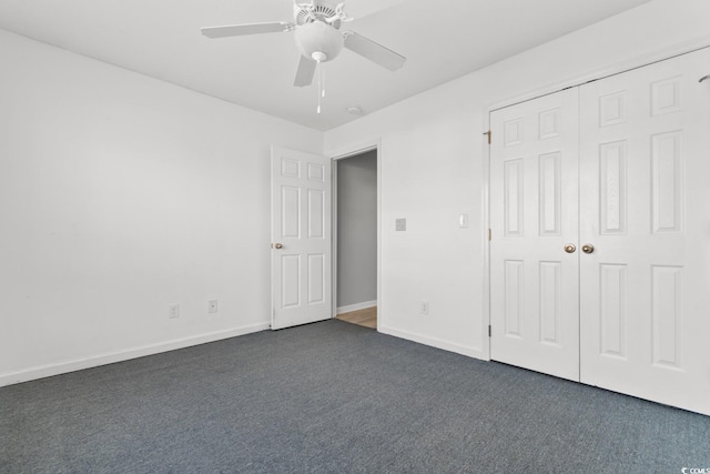 unfurnished bedroom featuring dark colored carpet, ceiling fan, and a closet