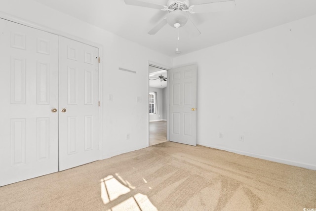 unfurnished bedroom featuring ceiling fan, light colored carpet, and a closet