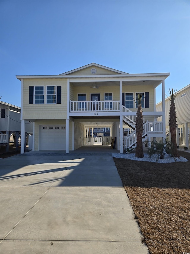 coastal inspired home with driveway, covered porch, stairway, and a carport