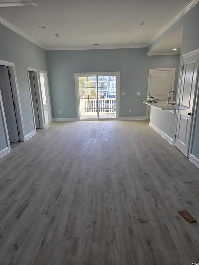 unfurnished living room featuring baseboards, ornamental molding, wood finished floors, and recessed lighting