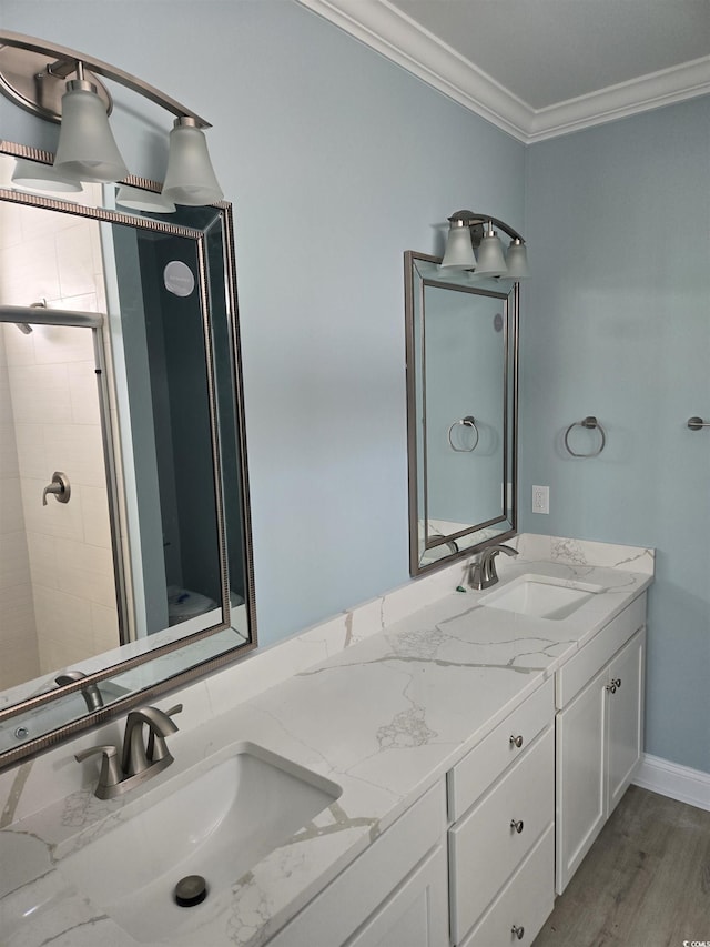 bathroom with wood finished floors, double vanity, ornamental molding, and a sink