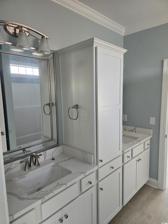 bathroom with baseboards, wood finished floors, crown molding, and vanity