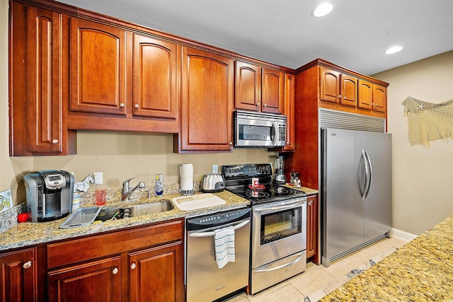 kitchen with light tile patterned floors, light stone counters, stainless steel appliances, a sink, and recessed lighting