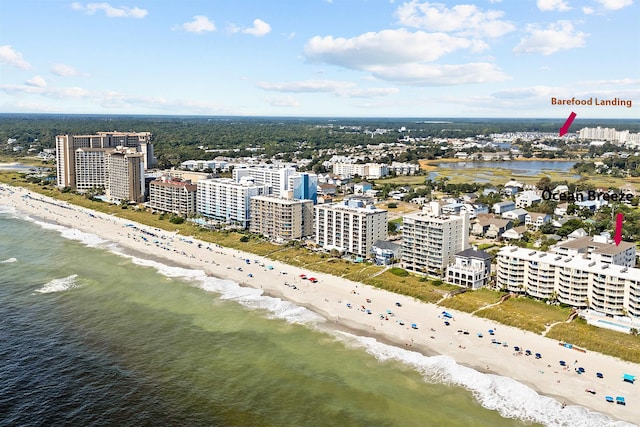 drone / aerial view featuring a water view, a beach view, and a city view