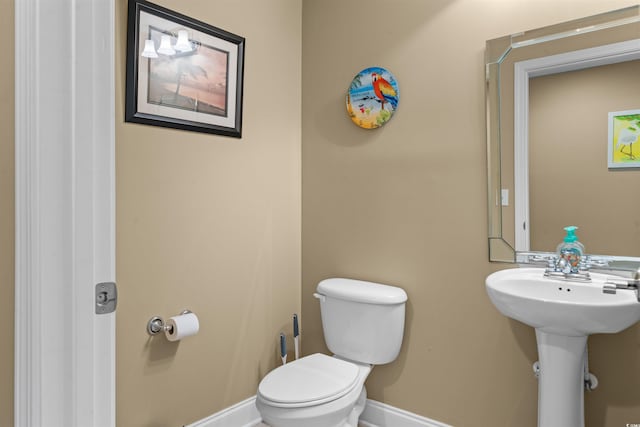 half bath featuring a sink, toilet, and baseboards